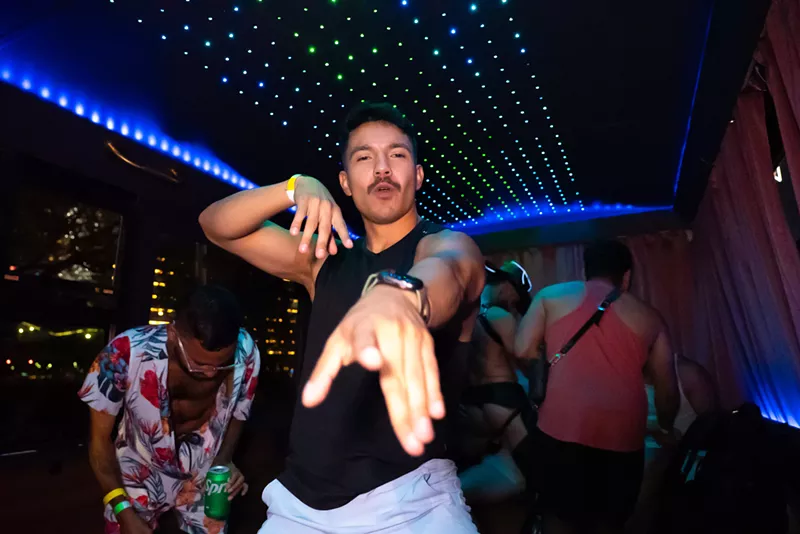 Image: a man poses for the camera inside a neon-lit party bus
