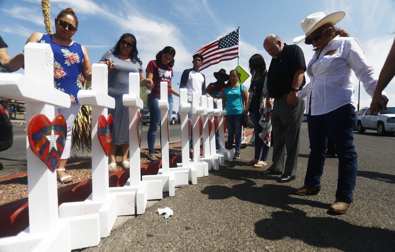 Volunteers pray over crosses memorializing the victims of a mass shooting that left at least 22 people dead in El Paso.
