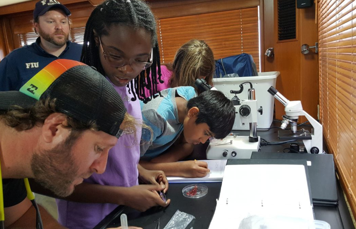 Students study plankton and algae samples aboard the research vessel the Angari. - PHOTO COURTESY OF RACHEL PLUNKETT VIA ANGARI