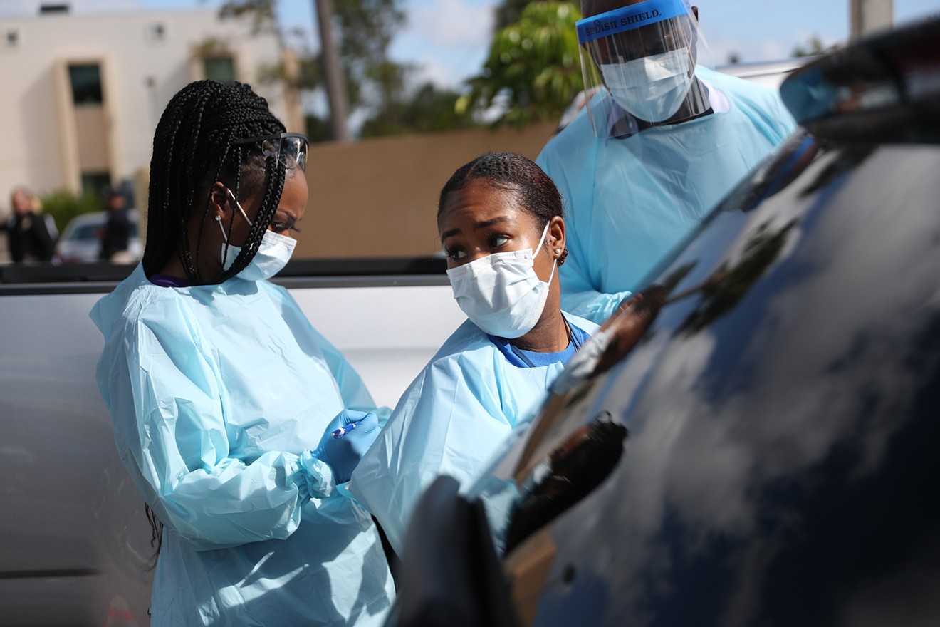 Healthcare workers wear protective gear at a drive-thru testing center in West Palm Beach.