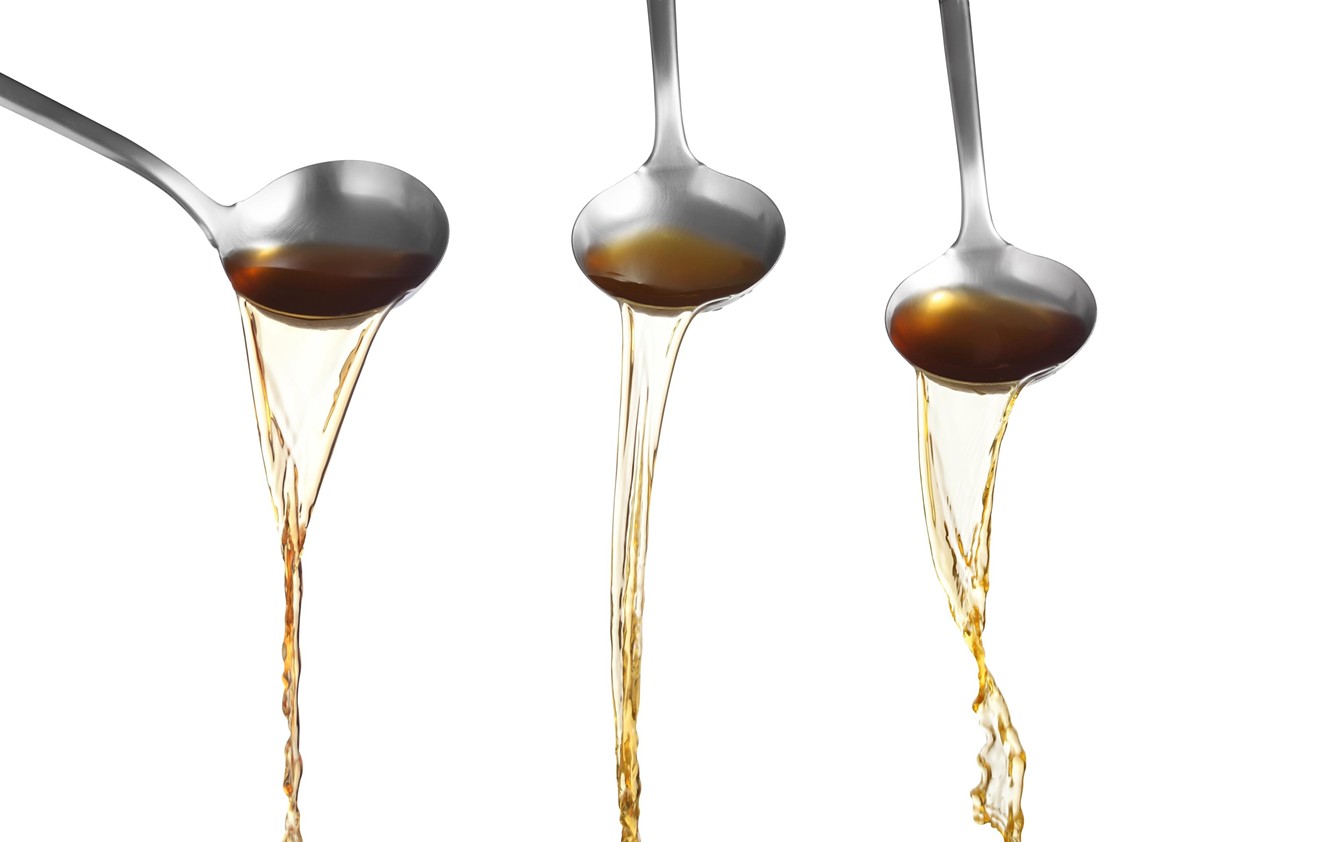 A golden liquid streams from three spoons in a completely innocuous stock photo.